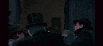 the joker is wearing a tuxedo and bow tie and has a flower in his lapel .