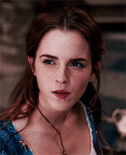 a close up of a woman wearing a blue shirt and a necklace