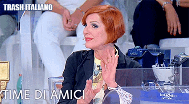 a woman with red hair is sitting in front of a sign that says trash italiano