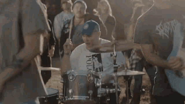 a man wearing a polo shirt is playing drums in front of a crowd