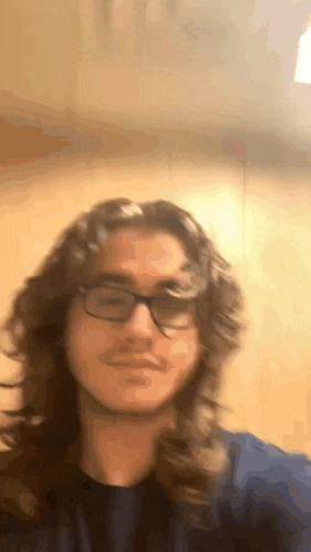 a man with long curly hair and glasses is taking a selfie