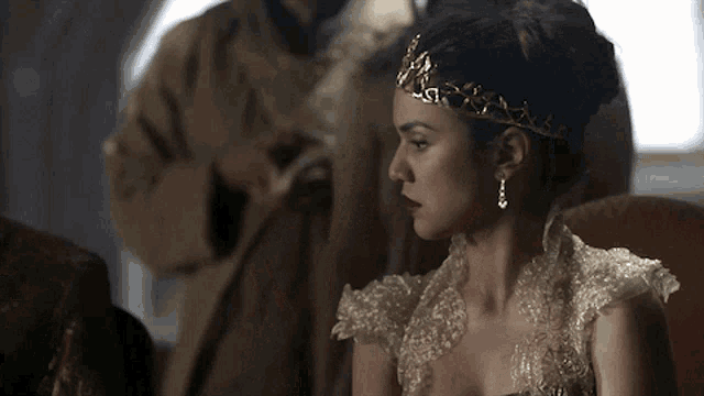 a woman wearing a tiara and earrings looks at the camera