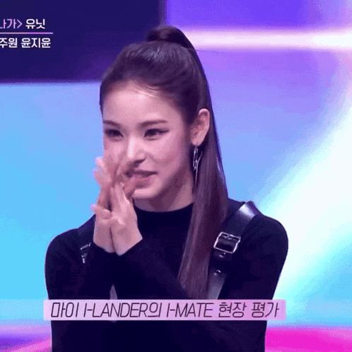 a girl with a ponytail is clapping her hands in front of a sign that says i-lander