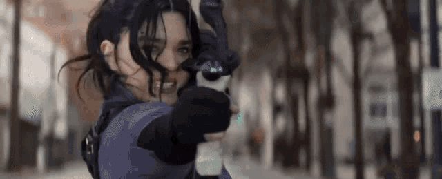 a woman in a purple outfit is holding a bow and arrow in her hand .
