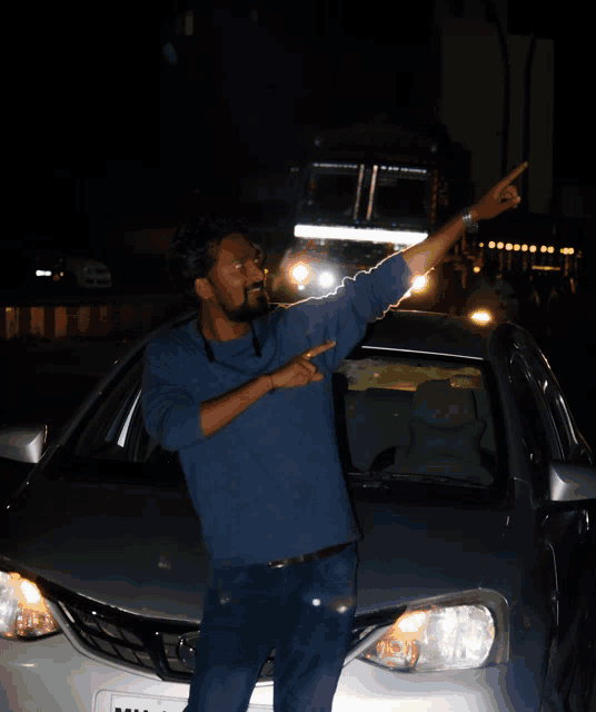 a man standing in front of a silver car with a license plate that says ' nc ' on it