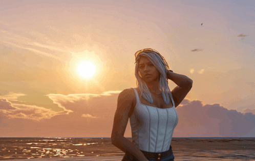 a woman stands on a beach at sunset