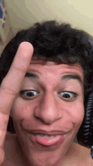 a man is making a funny face with his finger on his forehead
