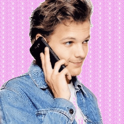 a young man in a denim jacket talking on a cell phone