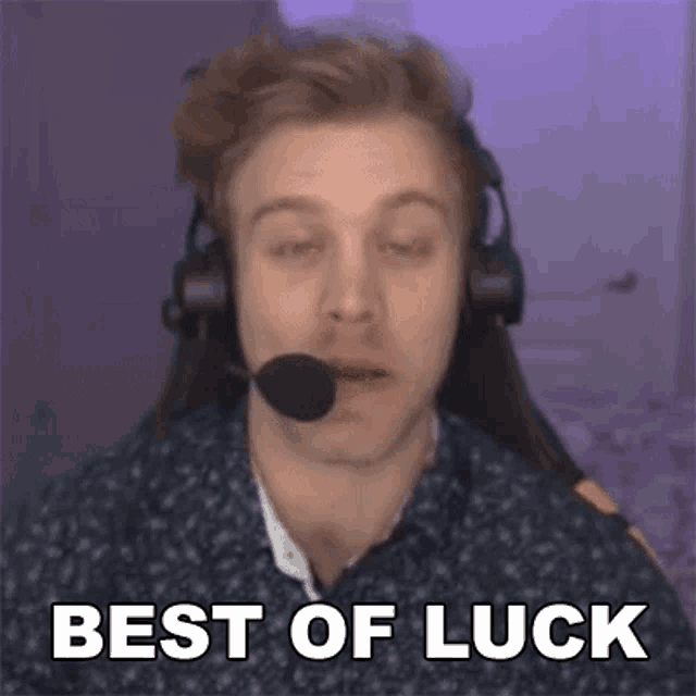 a man wearing headphones and a microphone is sitting in front of a computer screen and saying `` best of luck '' .