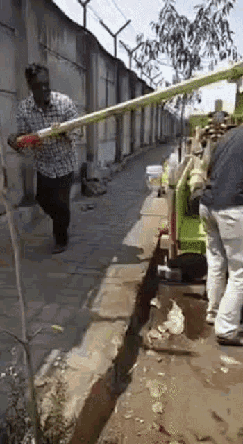 a man is walking down a sidewalk while holding a hose .