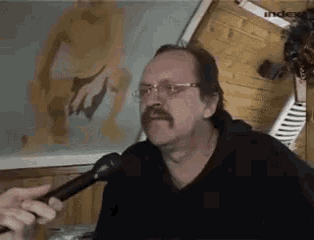 a man with a mustache is holding a microphone