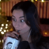 a woman is drinking from a cup through a straw .