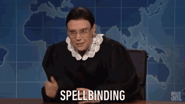 a woman in a judge 's outfit says spellbinding while sitting at a desk