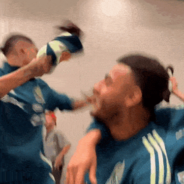a blurry picture of two men fighting with one wearing a blue adidas shirt