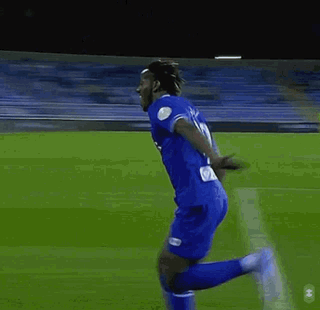a soccer player in a blue uniform is running on the field .