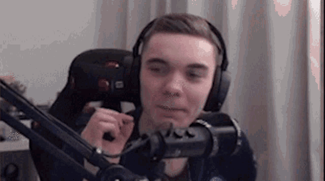 a young man wearing headphones is sitting in front of a microphone in a chair .