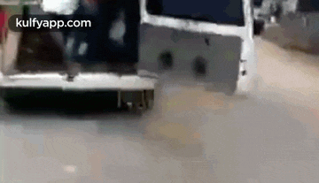 a white van is driving down a street with its trunk open .