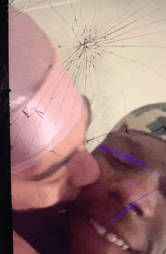 a broken mirror shows a woman 's face and a purple balloon