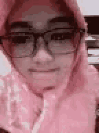 a close up of a woman wearing glasses and a pink scarf .