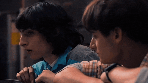 a group of young men are sitting next to each other and looking at something .