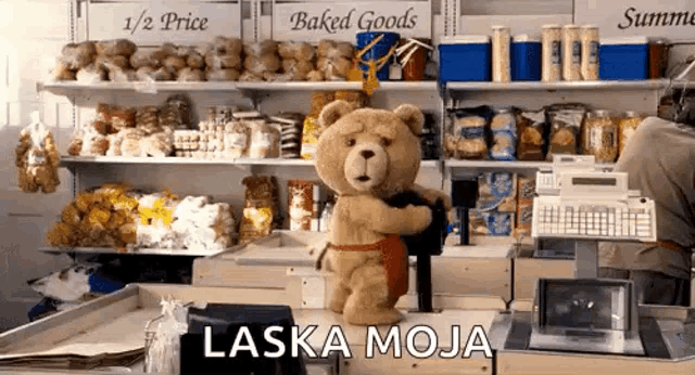 a teddy bear is hugging another teddy bear in a store and the words laska moja are on the counter