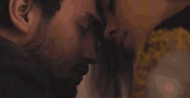 a man and a woman are kissing with their foreheads touching .
