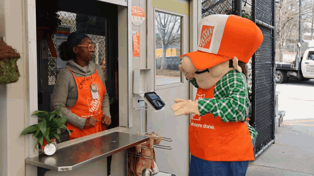 a home depot mascot talks to a woman behind the counter