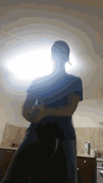 a man in a black shirt is dancing in the kitchen