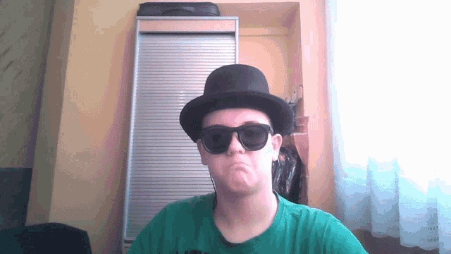 a man wearing a top hat and sunglasses is making a face