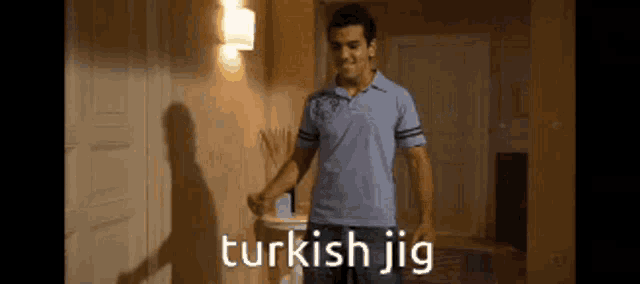 a man in a blue shirt is standing in a room with the words turkish jig written on the screen