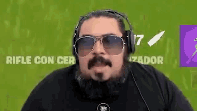 a man with a beard is wearing headphones and sunglasses while playing a video game .