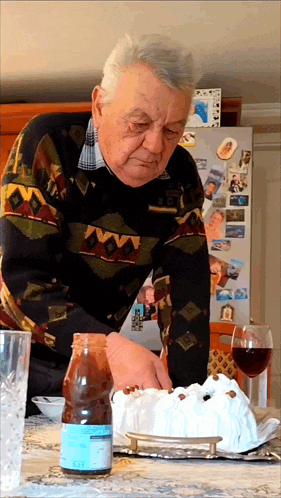 a man is cutting a cake in front of a refrigerator with a picture of a woman on it
