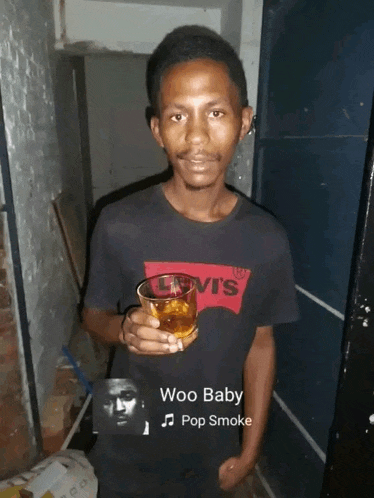 a man in a levi 's shirt holds a glass of whiskey
