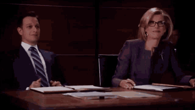 a man and a woman are sitting at a table with papers on it