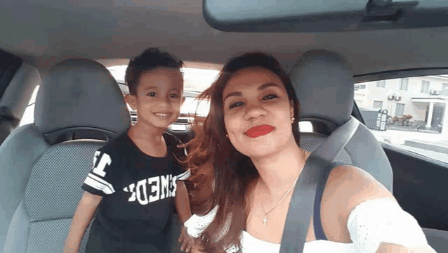 a woman and a child in a car with the boy wearing a shirt that says swedish