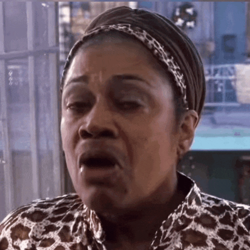 a woman wearing a headband and a leopard print shirt is making a face