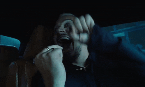 a man with a beard and earrings is screaming in a car