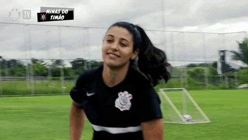 a female soccer player is smiling in front of a tv screen that says minas do timado