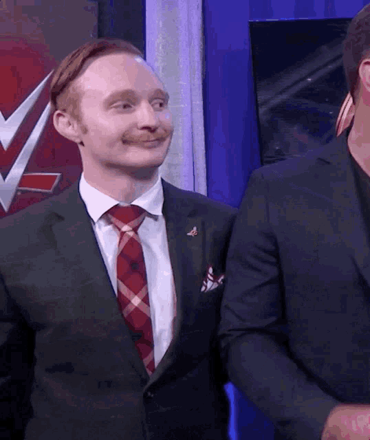 a man in a suit and tie stands next to another man in a suit and tie