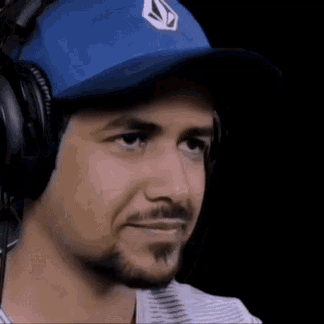 a man wearing headphones and a blue hat with a white triangle on it