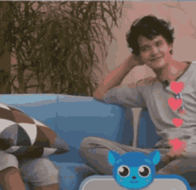 a man is sitting on a blue couch next to a blue cat toy