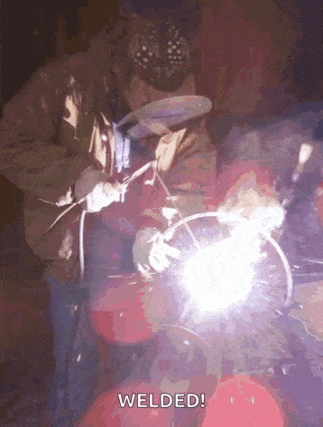 a man is welding a piece of metal with the words welded behind him .