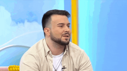 a man with a beard is wearing a tan shirt and white shirt