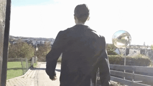 a man in a black jacket is walking down a road