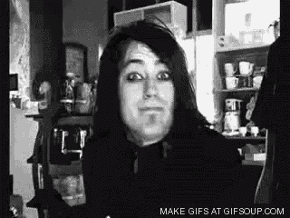 a black and white photo of a man with long hair making a face .
