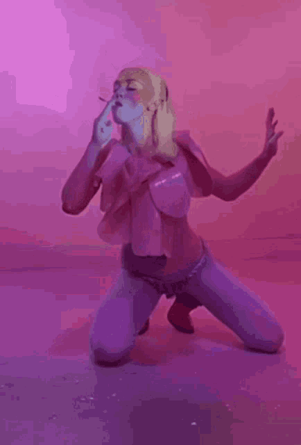 a woman is kneeling down and smoking a cigarette in a pink room