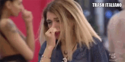 a woman is crying and covering her face with her hands while sitting at a table .