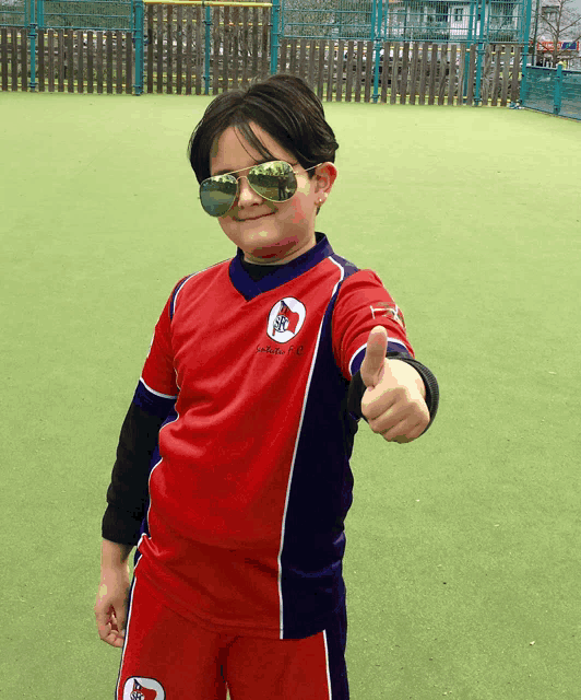 a young boy wearing sunglasses and a red shirt that says ' soccer club ' on it