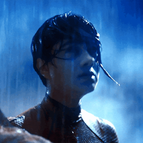 a close up of a person 's face in the rain with a blue background