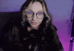 a woman wearing glasses and headphones is sitting in front of a purple light